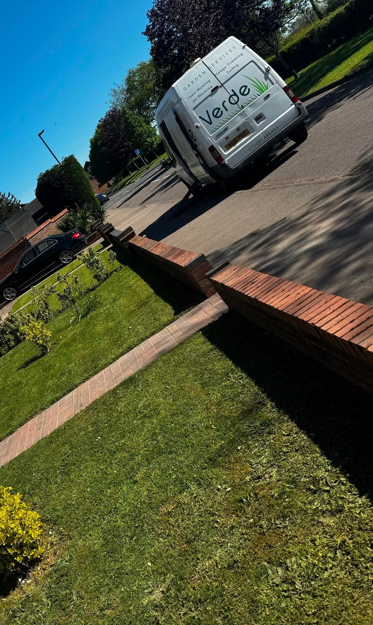 The Verde van on the road beside a freshly mown front lawn and brick path